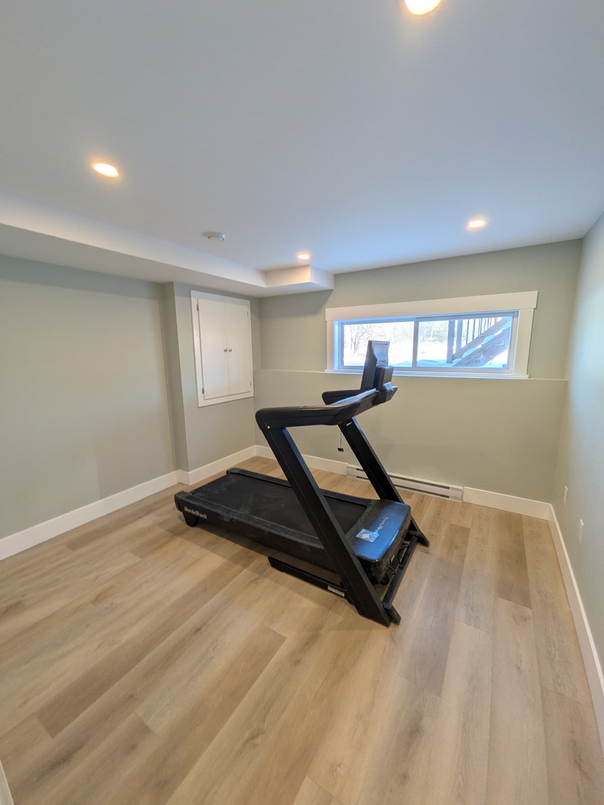 Finished basement fitness room with treadmill, light-toned flooring, and recessed lighting