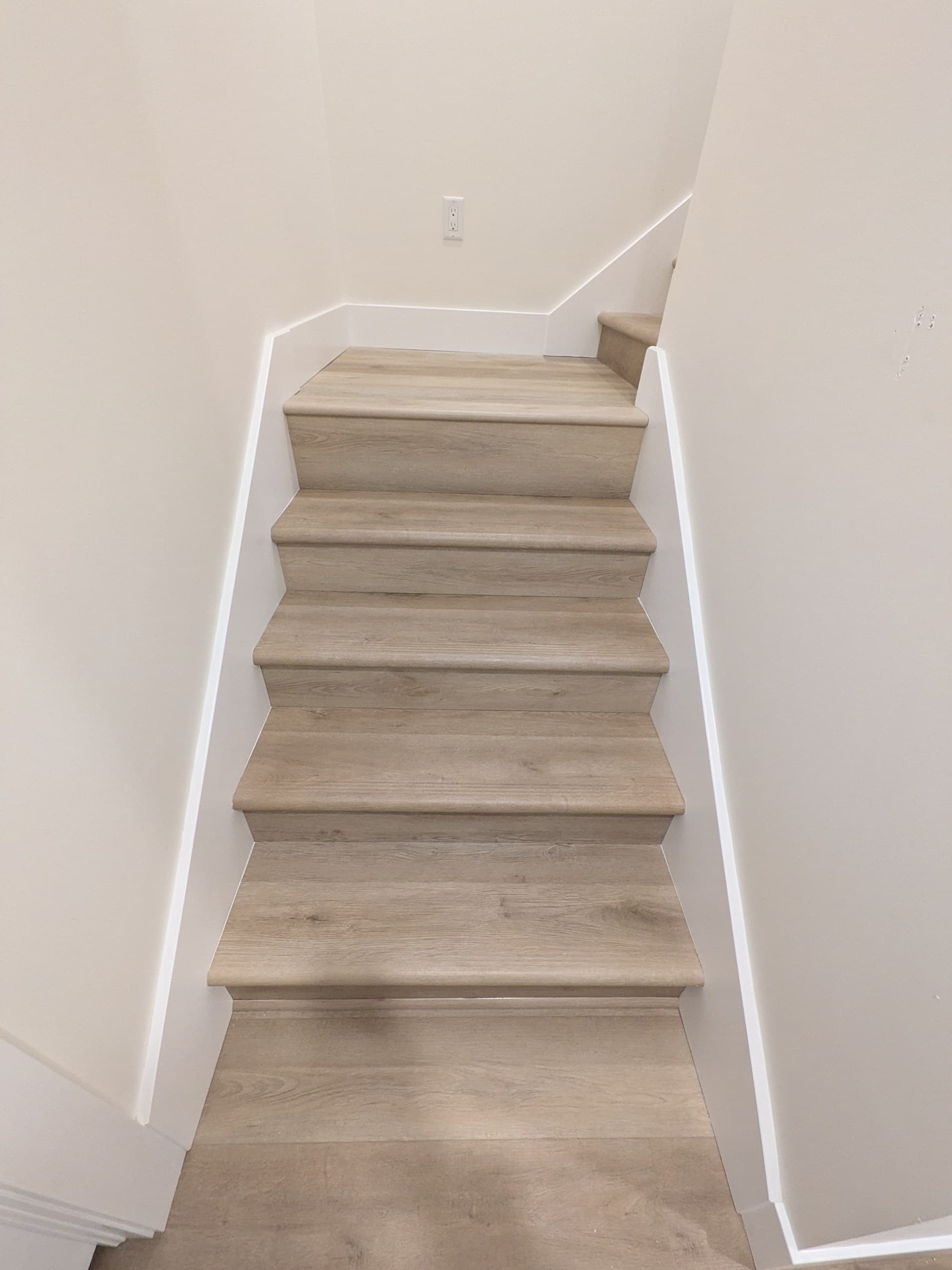 Finished basement staircase with light-toned treads and white walls