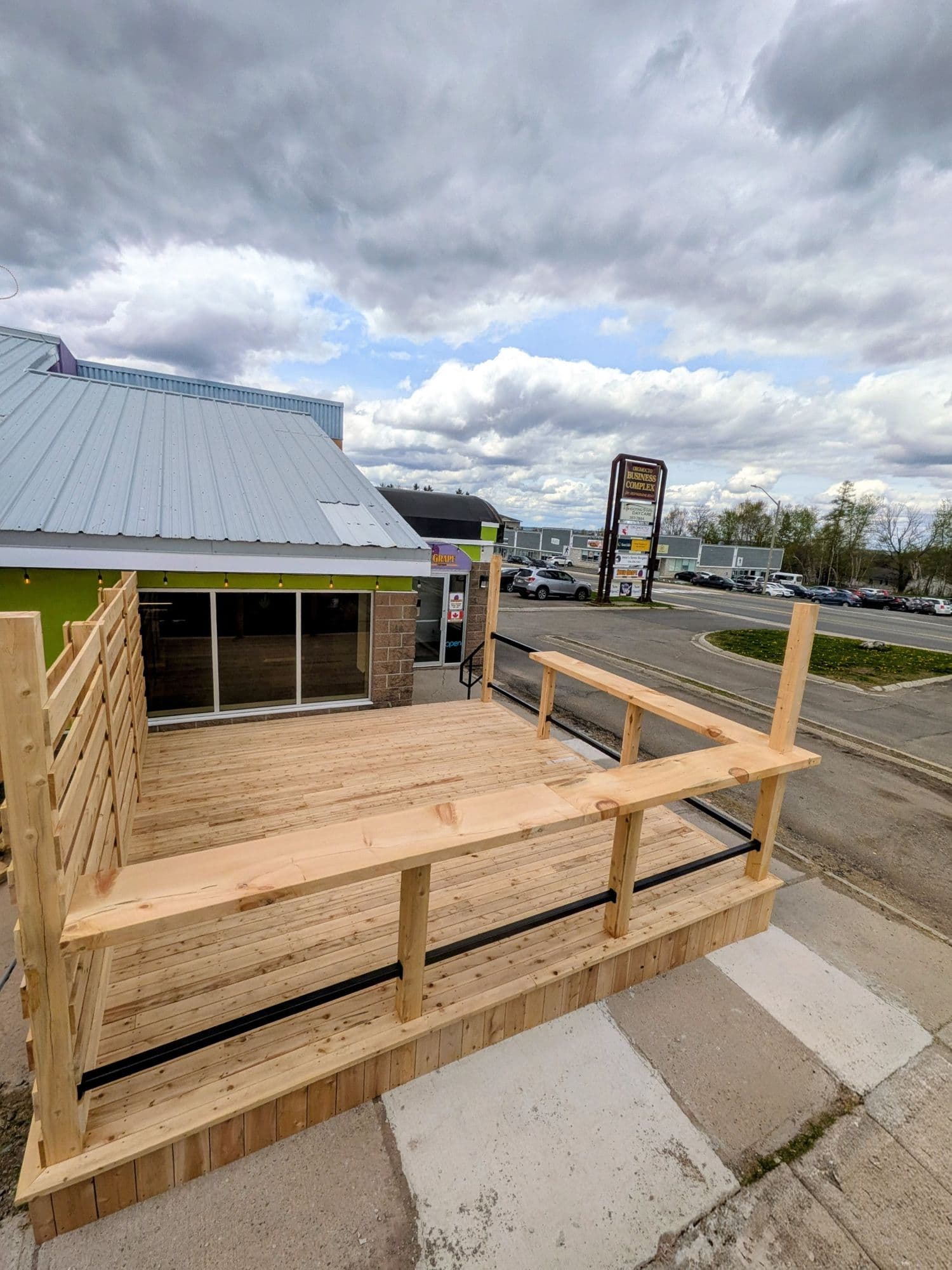 Finished deck with wood railing and stairs, overlooking a parking lot and street