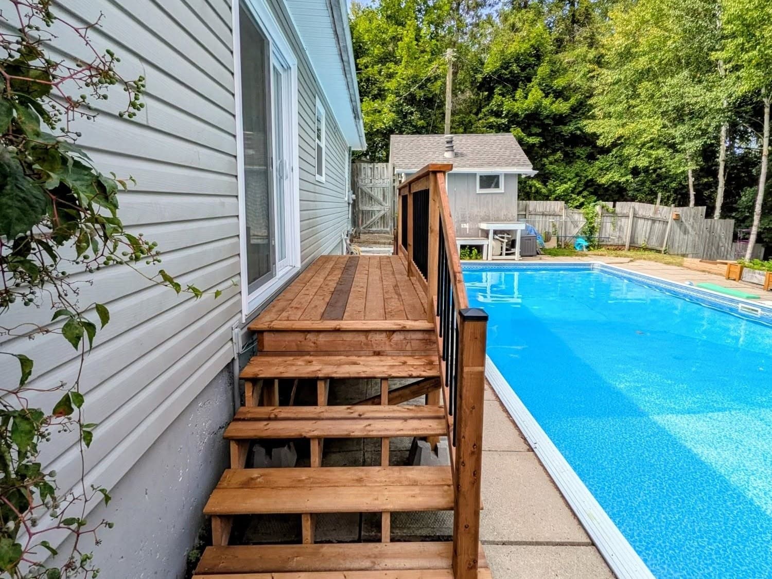 Wood deck and stairs beside a house and swimming pool
